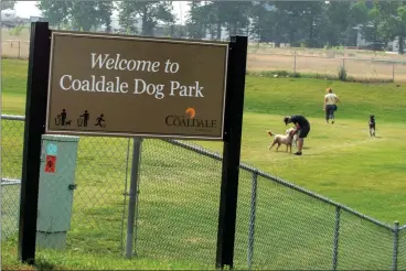  ?? HERALD PHOTO ?? A sign marks the top of an embankment at a staircase entrance to the Coaldale Dog Park as users take advantage of a warm summer day with their pups out on the grass.