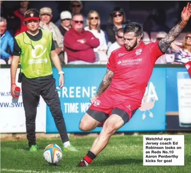  ??  ?? Watchful eye: Jersey coach Ed Robinson looks on as Reds No.10 Aaron Penberthy kicks for goal