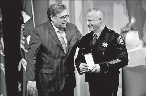  ?? OLIVIER DOULIERY/GETTY-AFP ?? Attorney General William Barr, left, awards Deputy Richard Hassna, from the Alameda County Sheriff’s Office in California, at a ceremony in Washington on Tuesday.