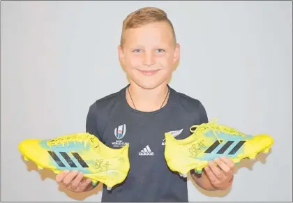  ??  ?? Riley Dickey holding boots Beauden Barrett wore during the 2018 season.