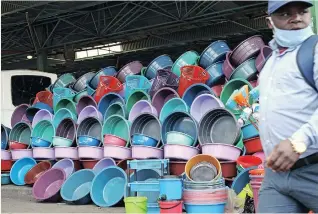  ?? (ANA) | DOCTOR NGCOBO African News Agency ?? A MAN walks past an array of colourful plastic dishes and bath tubs for sale at a bus rank in Warwick Avenue in Durban. According to the vendor, prices range from R30 up to R70, depending on the size and quality of the item.