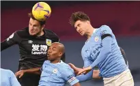  ??  ?? Manchester City’s John Stones and team-mate Fernandinh­o challenge Burnley’s Chris Wood in the air during Saturday’s clash