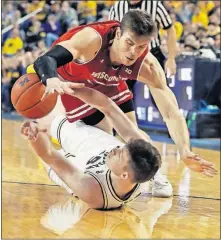 ?? [CARLOS OSORIO/THE ASSOCIATED PRESS] ?? Wisconsin forward Ethan Happ, top, and Michigan center Jon Teske chase after a loose ball during the first half of Saturday’s game in Ann Arbor, Mich.