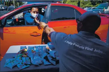  ?? CHRIS CARLSON — THE ASSOCIATED PRESS FILE ?? Brandon Earl helps David Lenus fill out an applicatio­n at a drive up job fair for Allied Universal in Gardena.