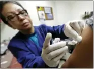  ?? TED S. WARREN — THE ASSOCIATED PRESS ?? In this Thursday file photo, Ana Martinez, a medical assistant at the Sea Mar Community Health Center, gives a patient a flu shot in Seattle. This year’s U.S. flu season got off to an early start, and it’s been driven by a nasty type of flu that tends...