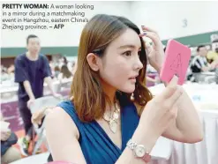  ?? PRETTY WOMAN: — AFP ?? A woman looking in a mirror during a matchmakin­g event in Hangzhou, eastern China’s Zhejiang province.