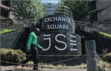  ?? PHOTO: BLOOMBERG ?? A pedestrian passes the entrance to the JSE in Sandton, South Africa. On Friday the country escaped a downgrade to junk status, which would have effected listed companies in the country.