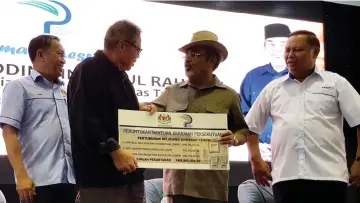  ??  ?? Tajuddin (second right) hands over a federal grant of RM8 million to the Tenom Area Farmers’ Organisati­on. Also seen are Sairin (right) and Raime.