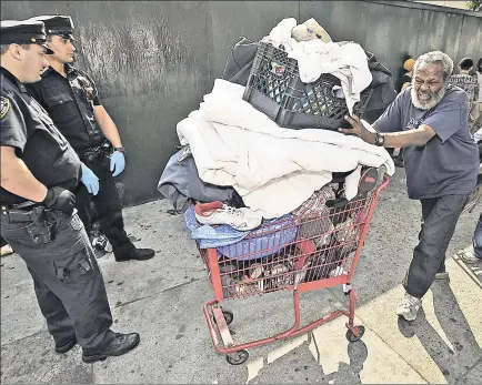  ??  ?? ROUSTED: Anthony Rainey wheels away his belongings as cops clear an encampment from 125th Street Wednesday.