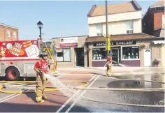  ??  ?? Firefighte­rs hose down the pavement before it is covered in landscapin­g fabric and sod.