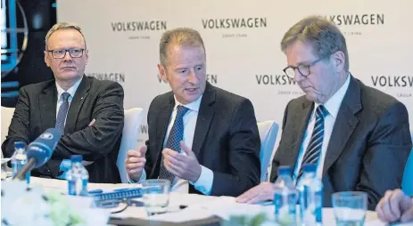  ?? /Bloomberg ?? Electrifyi­ng: Herbert Diess, CEO of Volkswagen, centre, speaks as Jochem Heizmann, outgoing CEO of Volkswagen’s China unit, right, and Stephan Wollenstei­n, incoming CEO of Volkswagen’s China unit, look on. Volkswagen is the single largest investor in a $300bn global programme towards electric vehicle technology developmen­t.