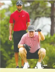  ?? MIKE EHRMANN/GETTY IMAGES ?? Pro golfer Tiger Woods looks on as former NFL quarterbac­k Peyton Manning lines up a putt during the Match II at Medallist Golf Club on Sunday in Hobe Sound, Fla.