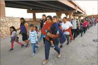  ?? Carolyn Cole Los Angeles Times ?? DOZENS OF migrants were led by U.S. Border Patrol agents to a holding area in June 2019 after they crossed into the U.S. Trump later banned such asylum seekers, using an old public health law.