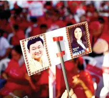  ?? — AFP file photo ?? A Pheu Thai Party supporter holding a placard with photograph­s of Thaksin and Yingluck, during a party’s election campaign rally in Bangkok.