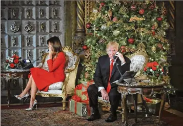  ?? BRUCE R. BENNETT / THE PALM BEACH POST ?? President Donald Trump and first lady Melania Trump answer phone calls at Mar-a-Lago on Sunday from children seeking updates on Santa Claus’ whereabout­s from NORAD’s Santa-tracking program.