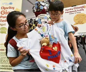  ??  ?? Teamwork pays off: Quah and Boay showing their winning T-shirt design at Gurney Plaza.