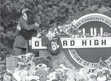  ?? JAKE MAY/THE FLINT JOURNAL VIA AP ?? Gov. Gretchen Whitmer embraces Oakland County Executive Dave Coulter as the two leave flowers and pay their respects Thursday at Oxford High School in Oxford, Michigan. The parents of a teen accused of killing four students at a Michigan high school were charged with involuntar­y manslaught­er Friday.