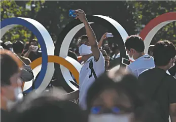 ?? Andrej Isakovic / AFP ?? Locals pose in front of the Olympic rings outside the Olympic Stadium in Tokyo.