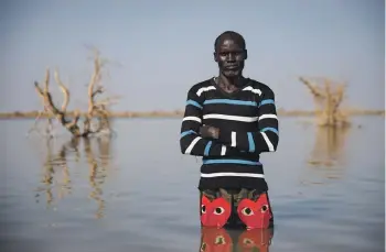  ?? GETTY IMAGES ?? John Malesh stands on flooded land where his house once stood in South Sudan. Asked about the threat of El Niño, he says: “If there is much rain this year, this land will no longer be here.” Climate change, including one of the strongest El Niño events of the past 75 years, has divided South Sudan into land that is experienci­ng either unpreceden­ted flooding or drought.