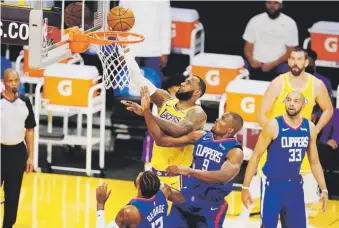  ?? ap ?? LeBron James, de los Lakers, evada la defensa de los Clippers para anotar durante el partido inaugural de la temporada 2020-21 de la NBA.