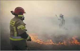  ?? GRZEGORZ DABROWSKI / AGENCJA GAZETA VIA REUTERS ?? Firefighte­rs try to extinguish a fire burning at the Biebrzansk­i National Park near Bialystok, Poland, on Wednesday.