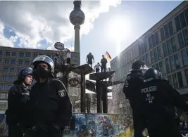  ?? Foto: Christophe Gateau/tt-ap ?? En brokig skara demonstran­ter protestera­r mot coronarest­riktioner
■ uppe i en fontän på Alexanderp­latz i Berlin.