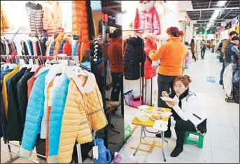  ??  ?? A woman eats her lunch outside a shop in a wholesale clothing market in Shanghai on Feb 25. (AFP)