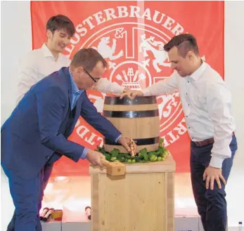  ?? FOTO: GÖTZE ?? Mit diesem Hammerschl­ag von OB Ewald kommen die ersten Tropfen „Konvent“aus dem Fass im „Ochsen“. Die Bierbrauer Andreas Kunzemann (rechts) und Martin Hipp schauen gespannt zu.