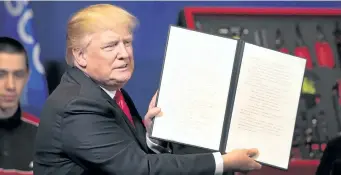  ?? SCOTT OLSON/GETTY IMAGES ?? U.S. President Donald Trump signs an executive order to try to bring jobs back to American workers during a visit to the headquarte­rs of tool manufactur­er Snap-On on Tuesday in Kenosha, Wis.