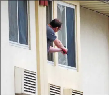  ?? FILE PHOTO BY JOHN BECHTOLD ?? Dennis O. Stokes points a gun out a second-floor window of the Super 8 motel in Kingston during the Jan. 2, 2017, standoff.