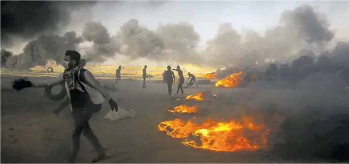  ?? AP ?? A sangre y fuego. Manifestan­tes palestinos queman cubiertas en la Franja de Gaza durante una nueva jornada de protestas contra Israel en la zona. Ya hubo más de 60 muertos.