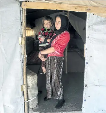  ?? RYAN REMIORZ/THE CANADIAN PRESS ?? A Yazidi woman and her child stand at the door of their tent at a camp for internal displaced persons on Wednesday, in Dohuk, Iraq. Canada has promised to accept hundreds of Yazidi refugees by the end of this year.