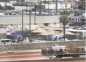  ?? Cedar Attanasio / Associated Press ?? Migrants are held Wednesday within a fenced-off area inside a temporary outdoor encampment where they’re waiting to be processed in El Paso, Texas.