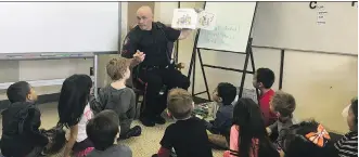  ?? BRYAN PASSIFIUME ?? Const. Don Johnson, a Calgary police school resource officer, is a familiar sight to students such as those in this Grade 1 class at St. Augustine School.