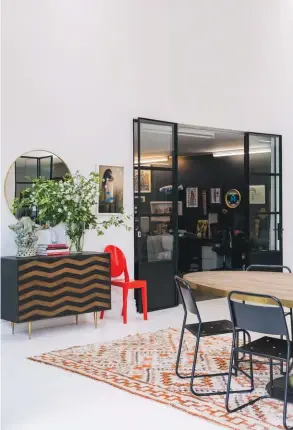  ??  ?? ABOVE In the casual dining area, a wild bunch of f lowers from the garden prettifies a sideboard from French Country Collection­s. The red Victoria Ghost chair is by Kartell. LEFT This living area near the stairs is decorated with a sofa from Dawson &amp; Co, and leather chairs and an ottoman bought in Sri Lanka. A side table from French Country Collection­s, a coffee table made in the Coromandel from kauri timber and an artwork by Micky Durang round out the scene. OPPOSITE A pair of plush velvet Knox chairs from French Country Collection­s creates a quiet conversati­on zone beside the wood-burning fire. The coffee table is from Città and the artwork is by Philippa Blair.