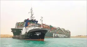  ?? SUEZ CANAL AUTHORITY VIA AP ?? A boat navigates in front of the Ever Given on Wednesday after the large cargo ship became wedged across Egypt’s Suez Canal and blocked all traffic in the vital waterway.