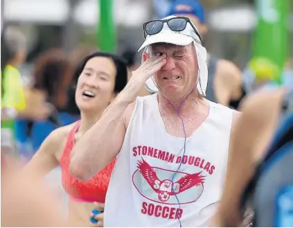  ?? JOE CAVARETTA/STAFF PHOTOGRAPH­ER ?? West Broward High School teacher Denis Rogrigues, 55, breaks down as he crosses the finish line in the Publix A1A Marathon in Fort Lauderdale on Sunday. Rodrigues taught for 12 years at Marjory Stoneman Douglas High School, the scene of Wednesday’s...