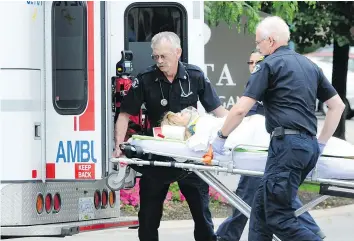  ?? — DON SIPOS/SPECIAL TO THE PROVINCE FILES ?? Paramedics load a victim into an ambulance in Kelowna after a shooting outside the Delta Grand hotel in August 2011.