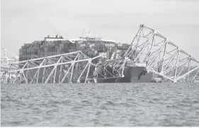  ?? FRANCE PRESSE ?? The steel frame of the Francis Scott Key Bridge sits on top of a container ship after the bridge collapsed collapsed in Baltimore, Maryland, on March 26, 2024. The bridge collapsed after being struck by a container ship, sending multiple vehicles and up to 20 people plunging into the harbor below. “Unfortunat­ely, we understand that there were up to 20 individual­s who may be in the Patapsco River right now as well as multiple vehicles,” Kevin Cartwright of the Baltimore Fire Department told CNN. Ship monitoring website MarineTraf­fic showed a Singapore-flagged container ship called the Dali stopped under the bridge.AGENCE