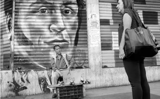  ?? AP ?? A street vendor sells bananas in front of a painting with the image of Venezuelan Independen­ce hero Simón Bolívar, in Caracas, Venezuela, on Tuesday, July 16.