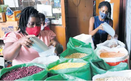  ?? PHOTOS BY CHRISTOPHE­R SERJU ?? Proprietor of Quality Grains, Sylvia Tomlinson-Hird (left), steps in to serve a customer during a busy period at her business place at 99 Newport Boulevard, St Andrew, on Thursday.