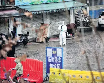  ?? PHOTO: REUTERS ?? Suspected epicentre . . . A worker in a protective suit walks through the closed Huanan Seafood Wholesale Market in Wuhan, which is linked to the outbreak of the new strain of coronaviru­s.