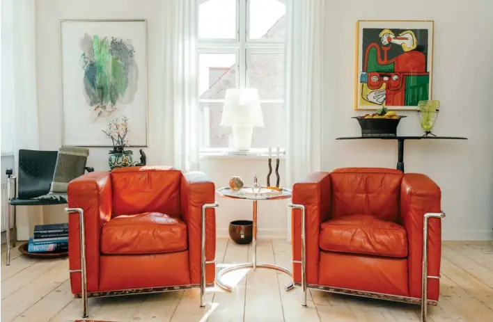  ??  ?? De to røde laenestole er "LC2" af Le Corbusier. Det lille runde glasbord er af Eileen Gray. Billedet på vaeggen er et sjaeldent litografi af Le Corbusier. Foto: Soffi Chanchira Larsen