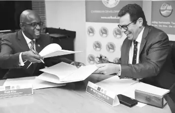  ?? — Desmond Brown/IPS photo ?? CTO Secretary-General Hugh Riley (left) and CDB President Dr Smith share a light moment during the signing of a partnershi­p agreement at CDB headquarte­rs.