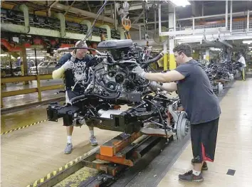 ?? — Reuters ?? Chrysler Group assembly workers lower an engine onto the frame of a 2014 Ram 1500 pick-up truck on the assembly line at the Warren Truck Plant in Warren, Michgan.
