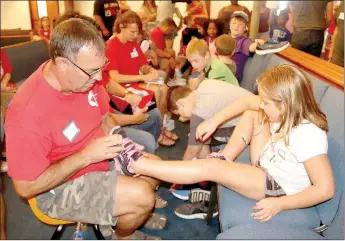  ?? LYNN KUTTER ENTERPRISE-LEADER ?? Jim Hendricks, a member of Farmington United Methodist Church, helps Haidyn Holt, 7, of Prairie Grove, find a new pair of shoes for school. Around 200 families came to the 14th annual Farmington Back-to-School Bonanza.