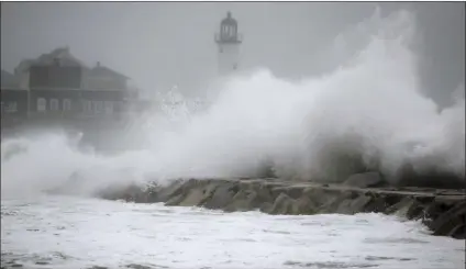  ??  ?? Waves crash against a seawall near the Scituate Lighthouse on Friday in Scituate, Mass. A major nor’easter pounded the East Coast on Friday, packing heavy rain and strong winds as residents from the mid-Atlantic to Maine braced for coastal flooding. AP...