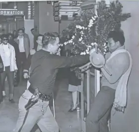  ?? jsonline.com/greensheet. GEORGE KOSHOLLEK/MILWAUKEE JOURNAL ?? A sheriff's deputy pins Lawrence Friend (right) against the wall while the two wrestle over a Christmas tree during a sit-in demonstrat­ion at the Milwaukee County welfare center on Dec. 5, 1968. For more photos from Milwaukee in 1968, go to