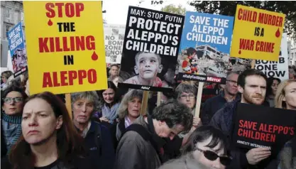  ?? — AFP ?? LONDON: Demonstrat­ors hold placards during a protest calling on the British government to take action to protect the children of the Syrian city of Aleppo outside Downing Street.