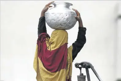  ?? EL PERIÓDICO ?? Una niña transporta en la cabeza un recipiente con agua en Lahore, en Pakistán.